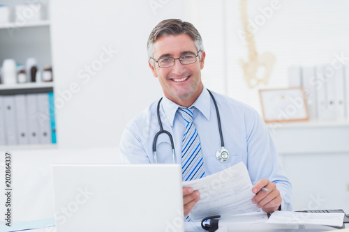 Male doctor holding document at table