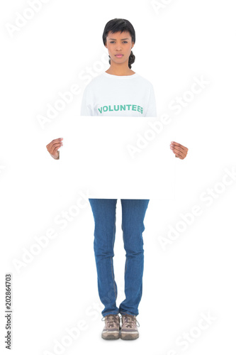 Unsmiling black haired volunteer holding a white panel in front of camera