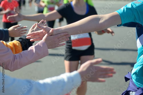 Marathon running race, support runners on road, child's hand giving highfive, sport concept 