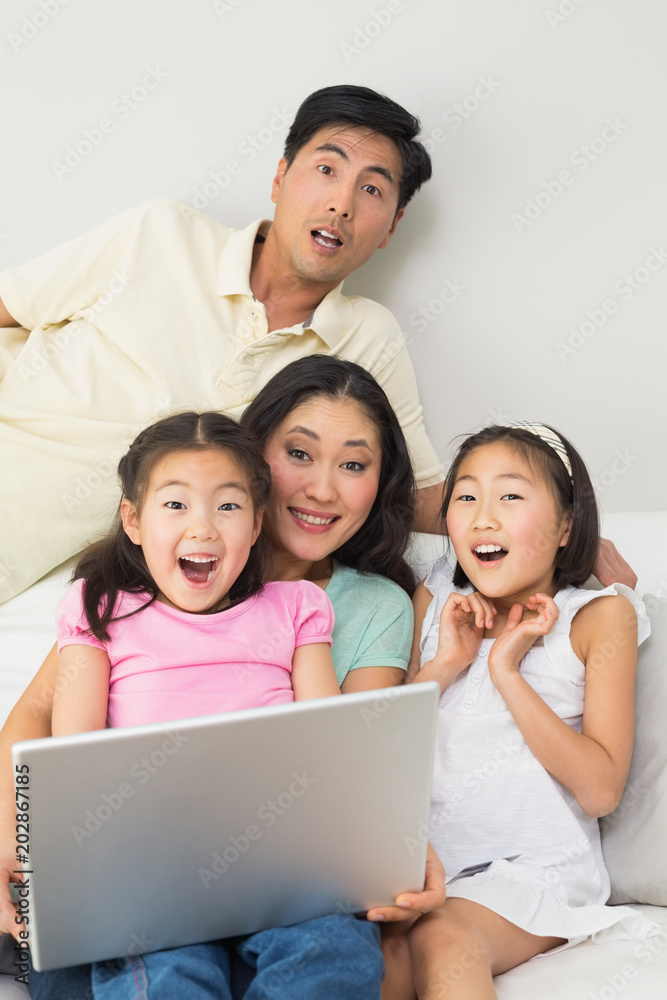 Happy shocked family of four using laptop Happy shocked family of four using laptop