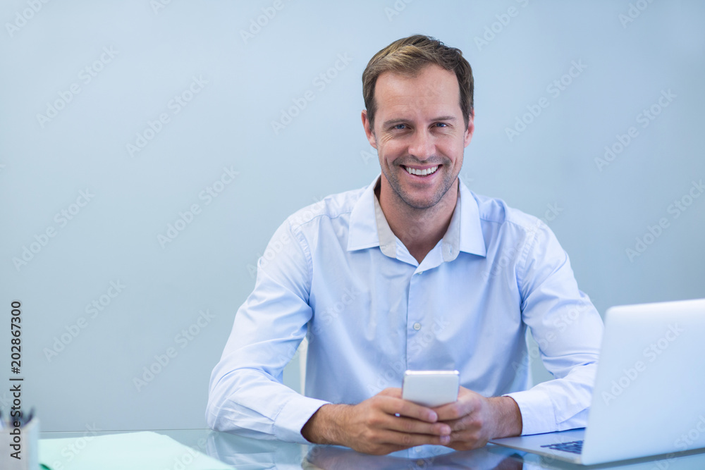 Smiling doctor using mobile phone in dental clinic Smiling doctor using mobile phone in dental clinic