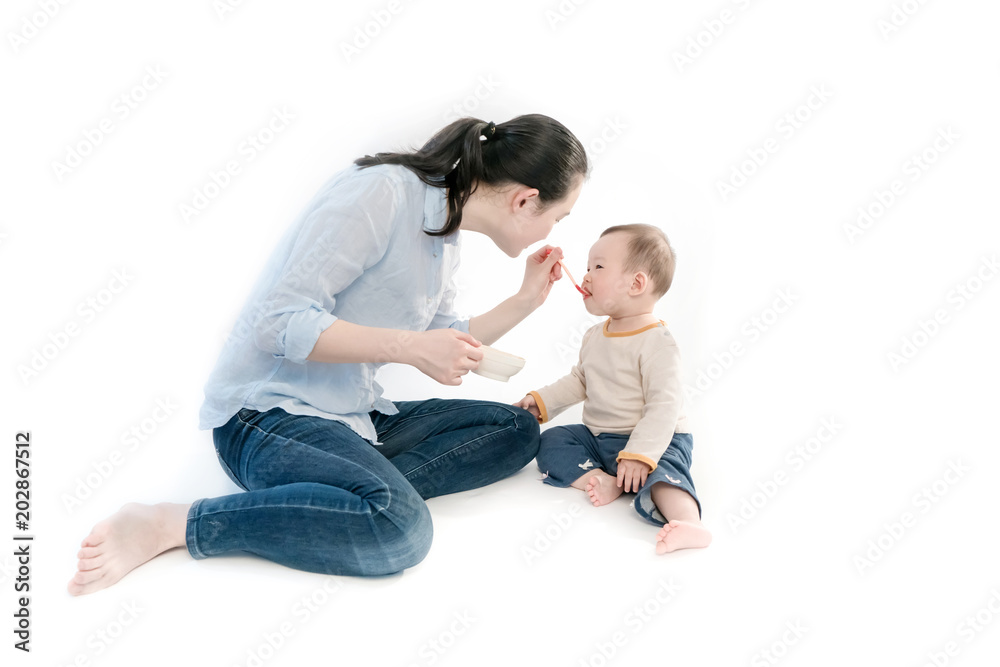Mother is feeding the child with fruit mud, white background Mother is feeding the child with fruit mud, white background