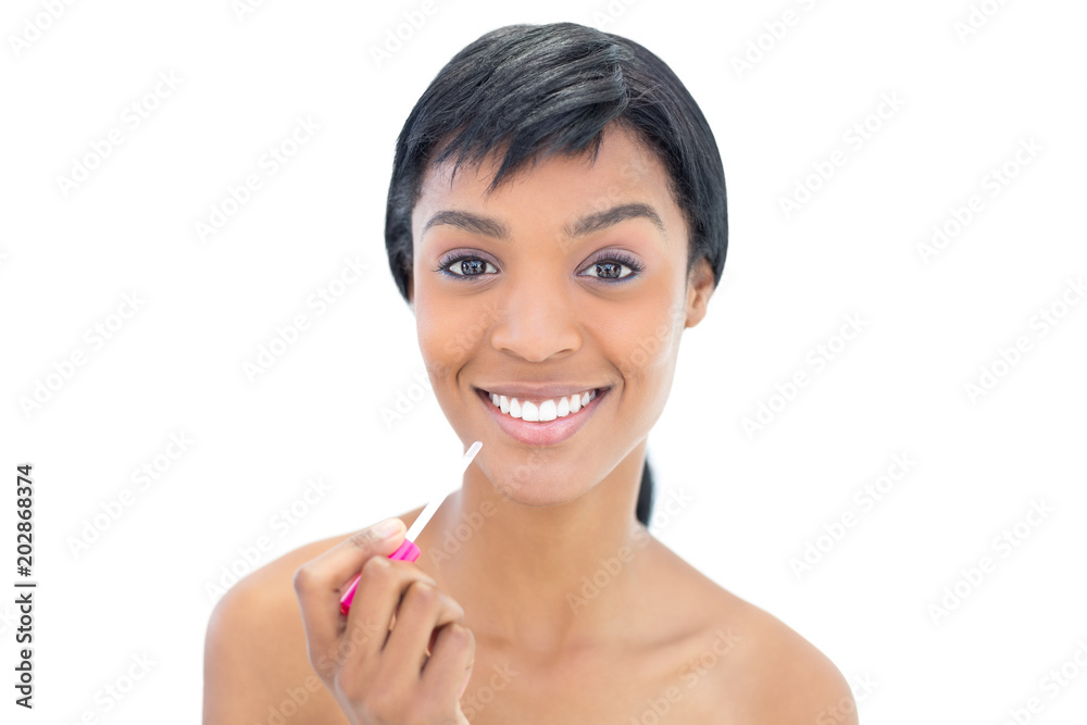 Joyful black haired woman applying gloss on her lips Joyful black haired woman applying gloss on her lips