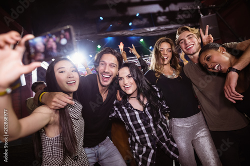 Cheerful friends taking selfie while enjoying at nightclub