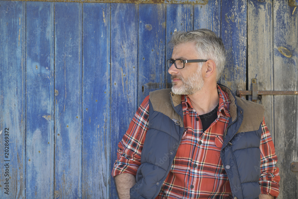 Portrait of farmer leaning on cowshed door