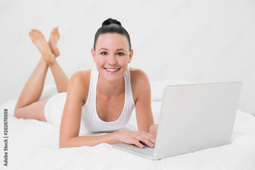 Smiling casual woman using laptop in bed Smiling casual woman using laptop in bed