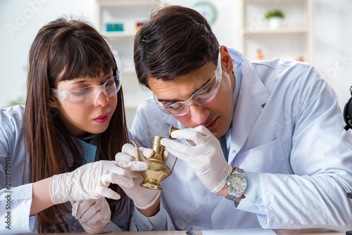 Two archeologists looking at ancient gold lamp