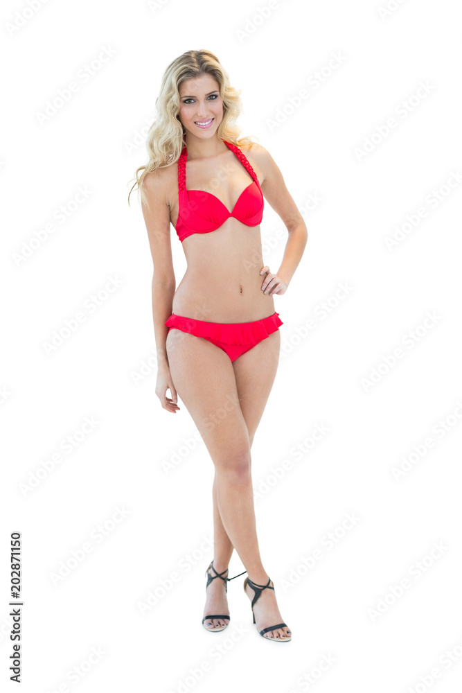 Beautiful smiling blonde model posing with hand on hips wearing red bikini Beautiful smiling blonde model posing with hand on hips wearing red bikini