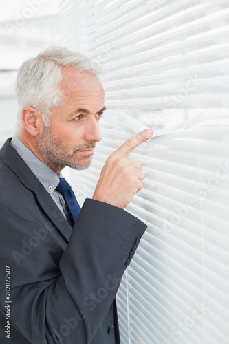 Serious mature businessman peeking in office