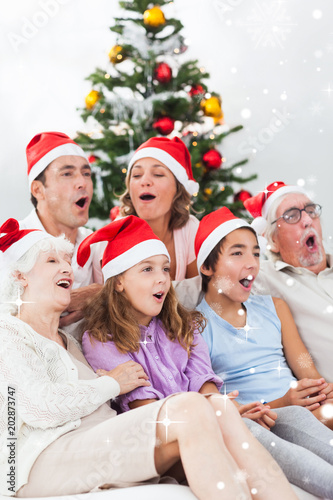 Obraz na plátně Extended family singing christmas carols against snow falling
