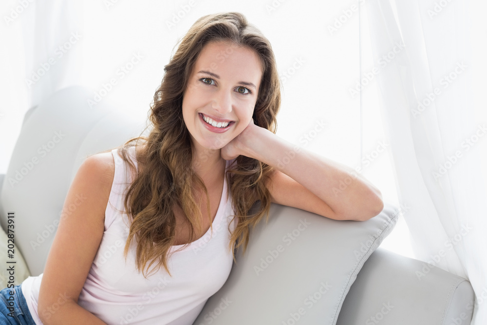 Smiling young woman sitting on sofa in living room Smiling young woman sitting on sofa in living room