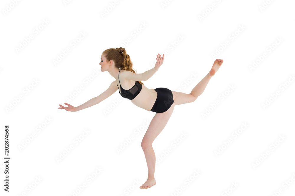 Side view of sporty woman standing on one leg
