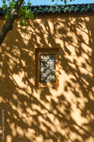 Shadows of the tree on the facade of the building with small window