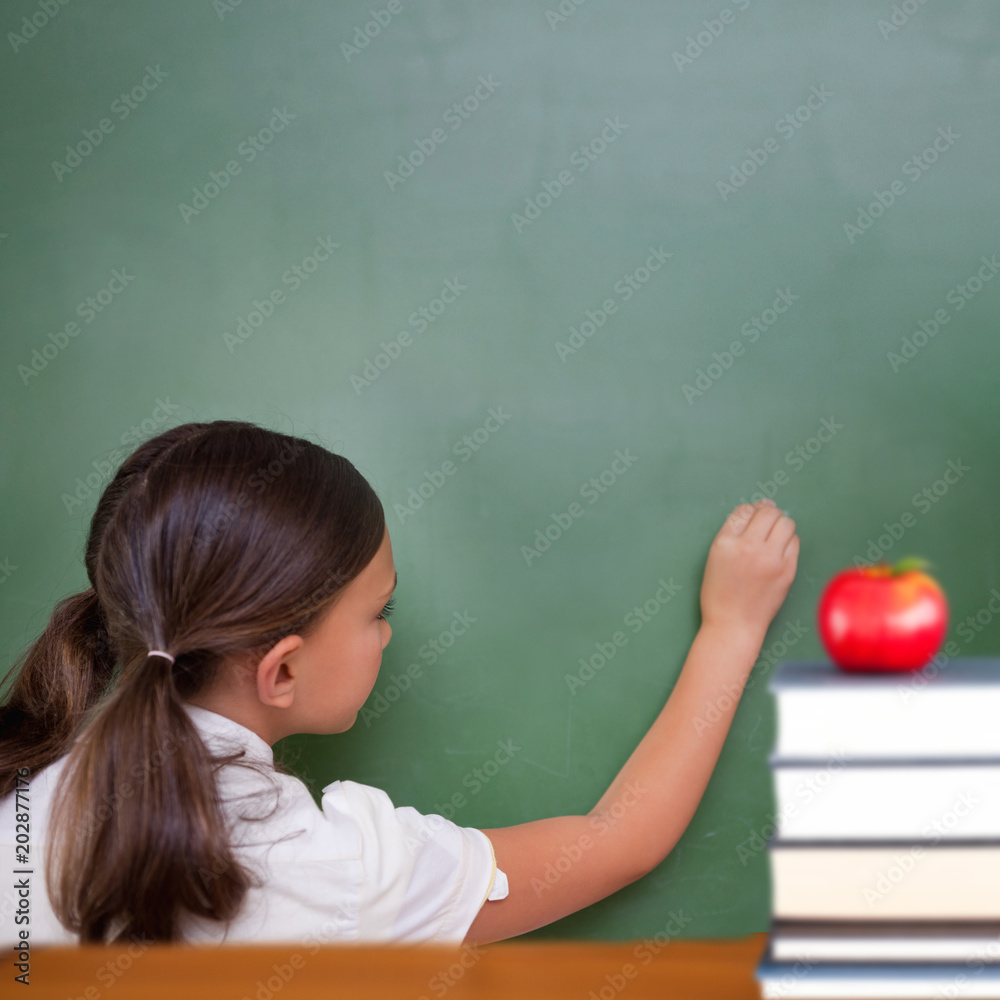 Red apple on pile of books against cute pupil writing on chalkboard Red apple on pile of books against cute pupil writing on chalkboard