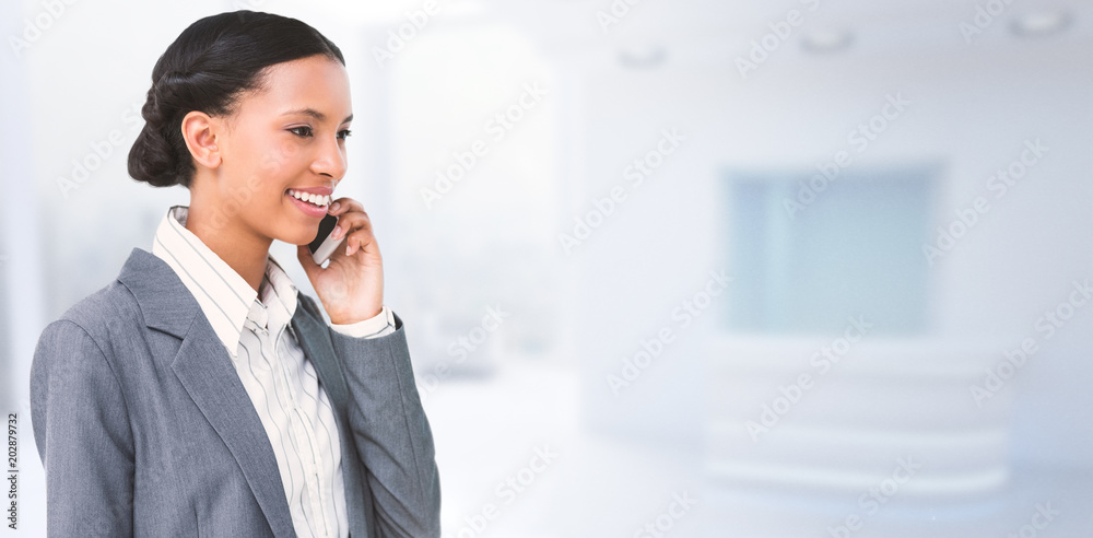 Obraz na plátně Smiling businesswoman using mobile phone against modern room overlooking city
