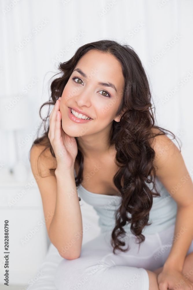 Smiling pretty brunette sitting on bed at home Smiling pretty brunette sitting on bed at home