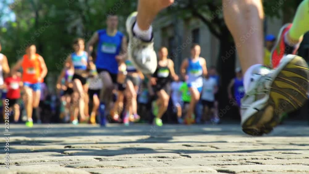 Unfocused blurred marathon runners. endurance challenge. Legs of runners on cobbles city street. Running competition