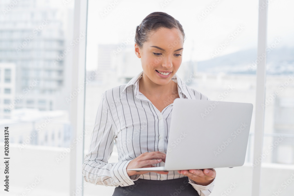 Businesswoman standing and typing on a laptop Businesswoman standing and typing on a laptop