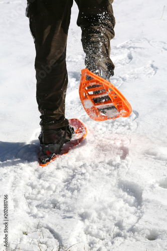 man runs with snowshoes in mountains on white snow