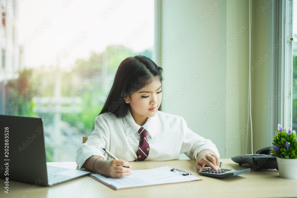 Girl looking a calculator for calculate on desk in office Girl looking a calculator for calculate on desk in office
