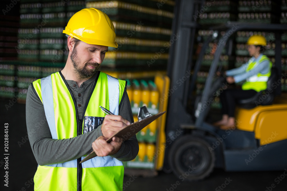 Factory worker writing on clipboard Factory worker writing on clipboard
