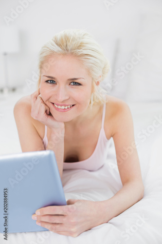 Free Download Smiling casual young blond with tablet PC in bed - GFXLoad