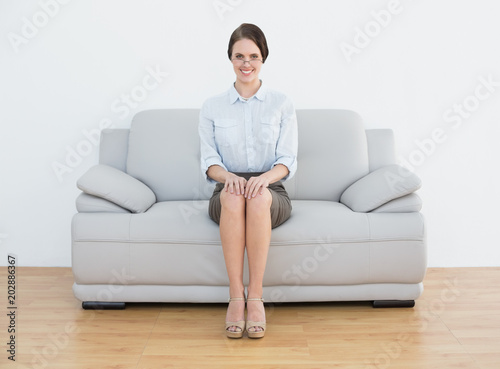 Full length of a smiling well dressed woman sitting on sofa