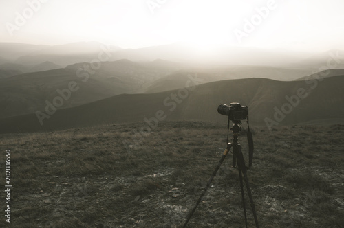 Camera mounted on a tripod, shooting a mountain landscape, toned image