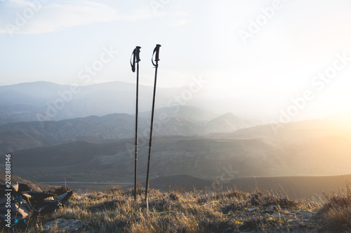 Ascent into the mountains, nordic walking sticks and a backpack, a traveler's set. Wonderful sunset in the background photo