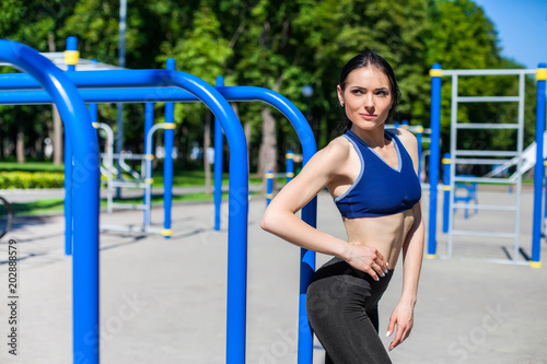 strong athletic girl in a bright blue sport bra and black leggings on the sport playground. Photo of an athlete girl with a beautiful sports body