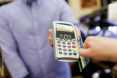 Picture of seller with terminal in hands and buyer with bank card.