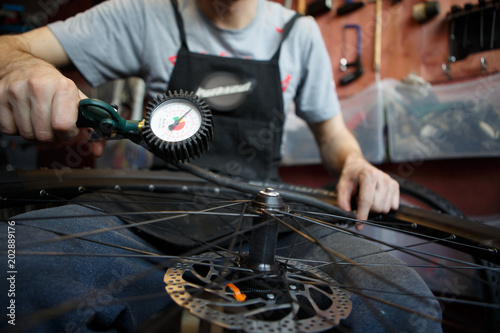 Photo of man repairing wheel of bicycle.