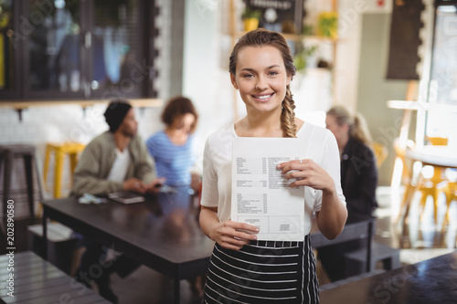 Smiling waitress standing with menu card at cafe