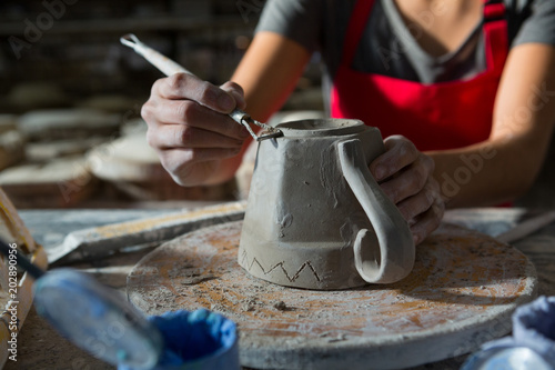 Female potter carving mug