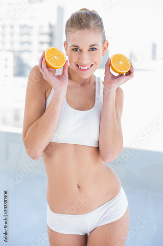 Gorgeous young blonde model holding two halves of an orange