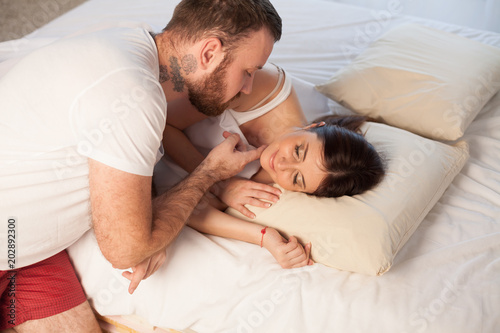 the man gently wakes the woman in bed in the morning photo