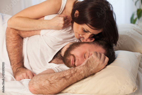 woman gently wakes up in the morning in bed man photo
