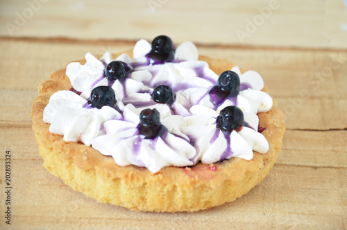 Berry mini tarts with the plate of berries over a white rustic wooden background, top view photo