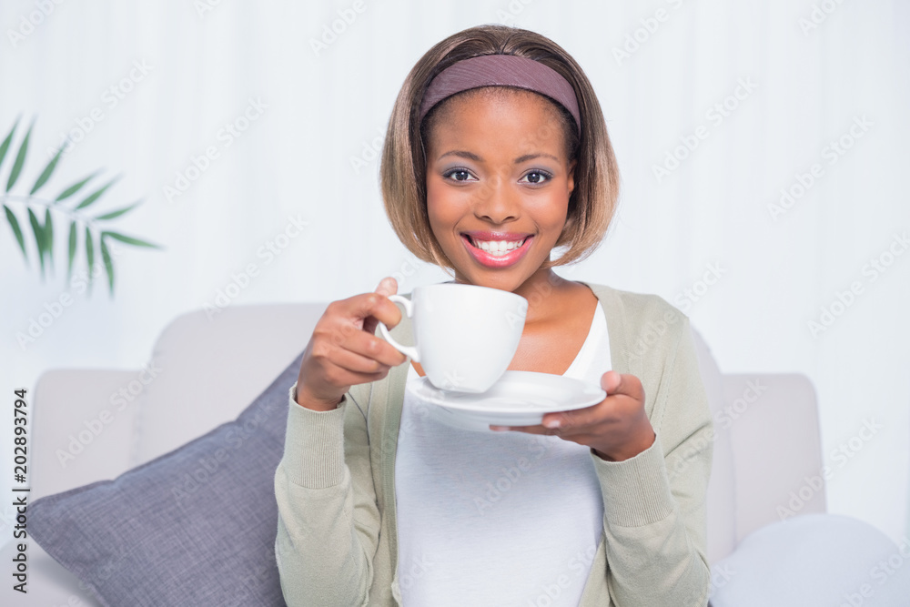 Smiling woman sitting on sofa holding coffee Smiling woman sitting on sofa holding coffee