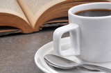 Tasse de café noir près d'un livre ouvert
