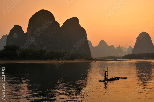 Silhouette of fishermen in Yangshuo, sunset at the LI river. Yangshuo is a popular tourist county and city near Guilin Guangxi China. © GISTEL