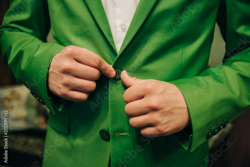 the groom fastens the buttons on his suit on the wedding day