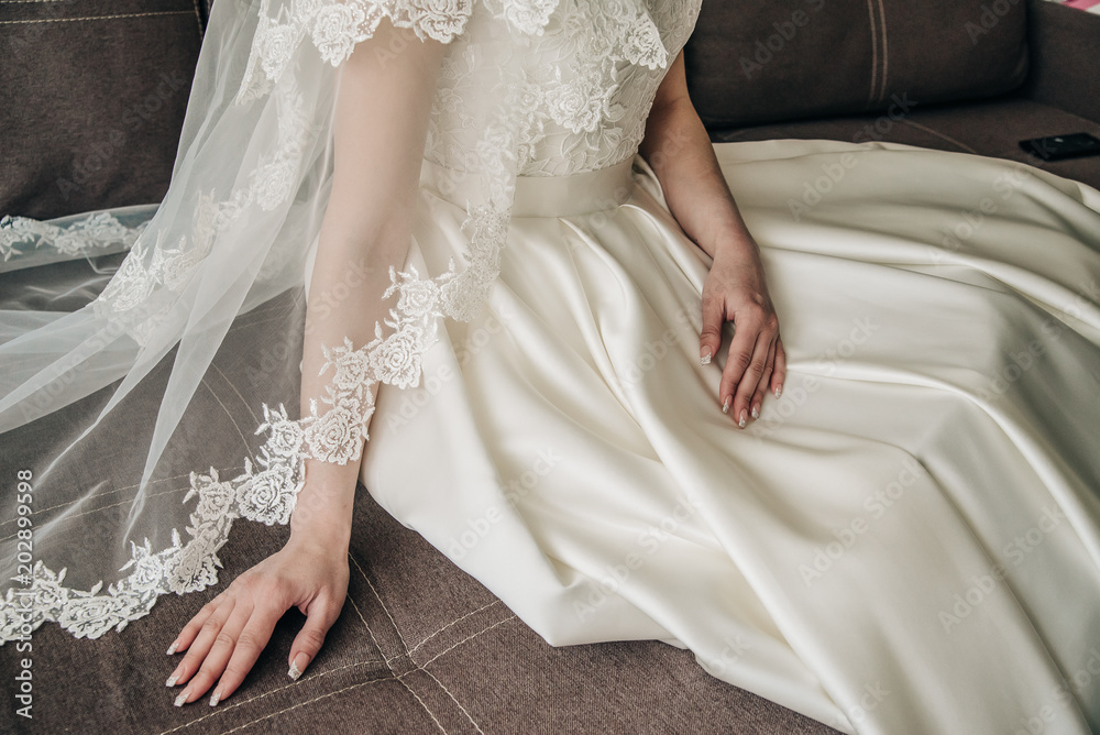 a luxurious bride with a long veil sits on the couch