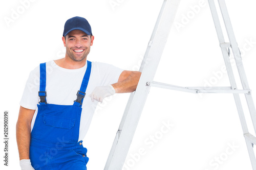 Handyman in overalls leaning on ladder