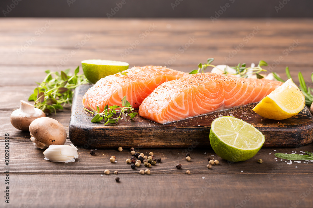 Fresh raw salmon fillet with aromatic herbs, spices on old wooden background with copy space. Fresh raw salmon fillet with aromatic herbs, spices on old wooden background with copy space.
