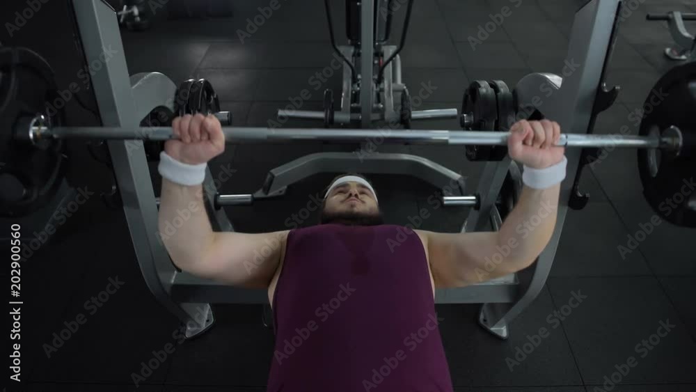 Chubby man unable to lift heavy barbell in gym during sport exercise, health Chubby man unable to lift heavy barbell in gym during sport exercise, health