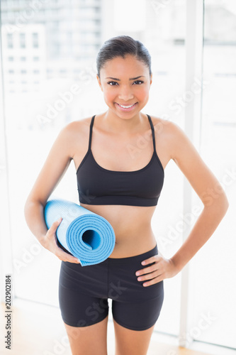 Lovely dark haired model in sportswear carrying a blue exercise mat © WavebreakmediaMicro