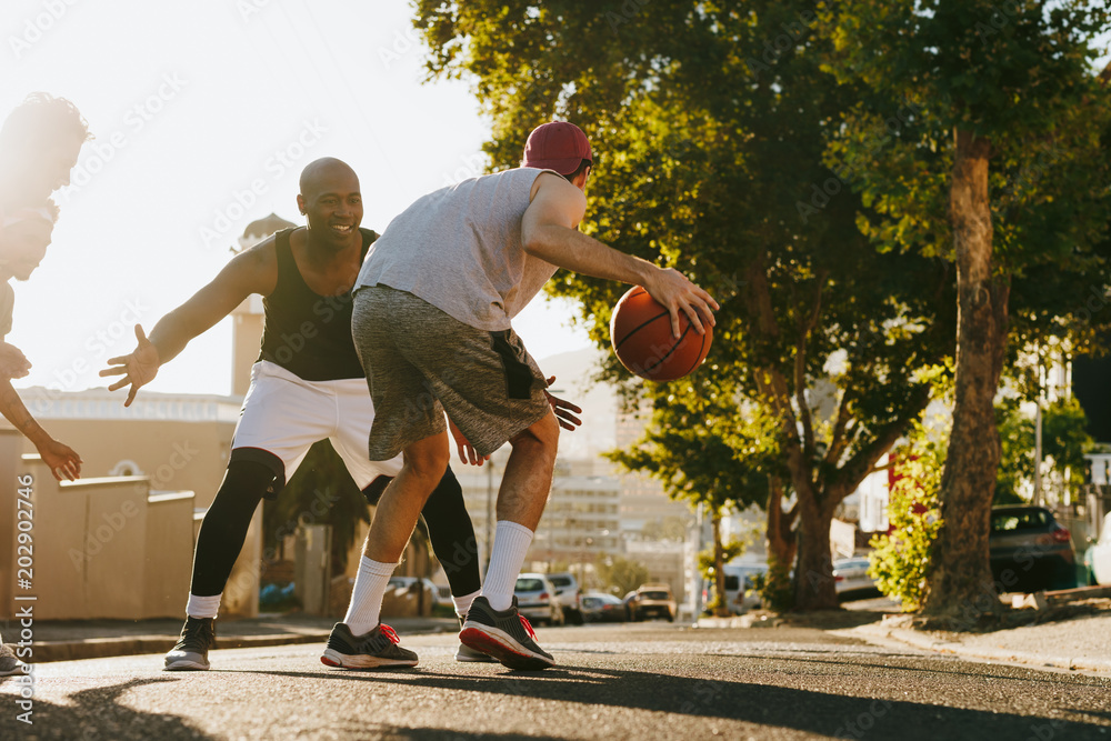 Naklejka premium Men playing basketball on street