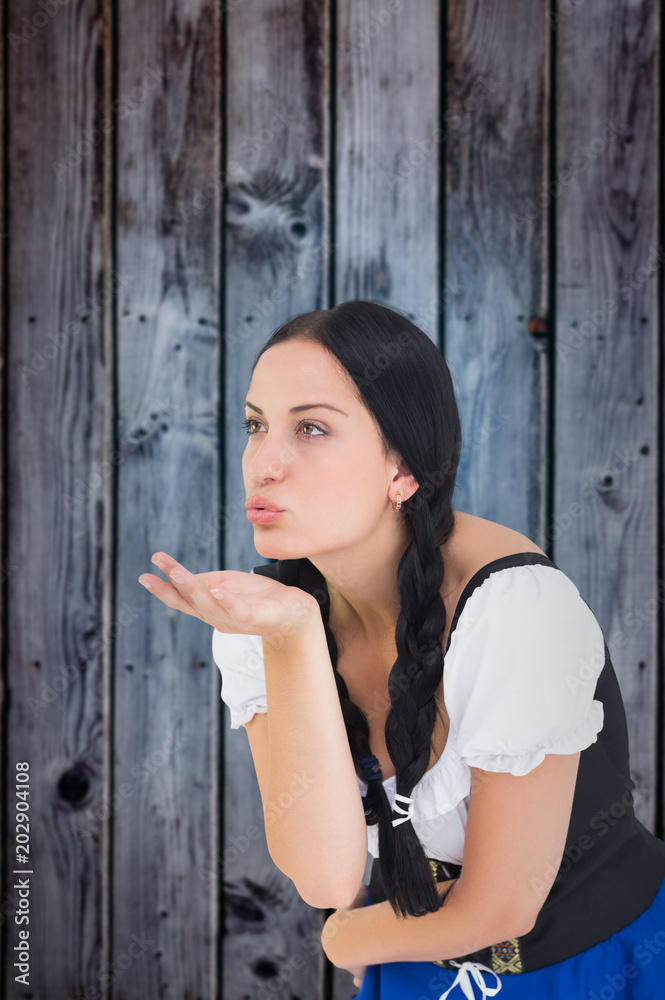 Pretty oktoberfest girl blowing a kiss against grey wooden planks Pretty oktoberfest girl blowing a kiss against grey wooden planks