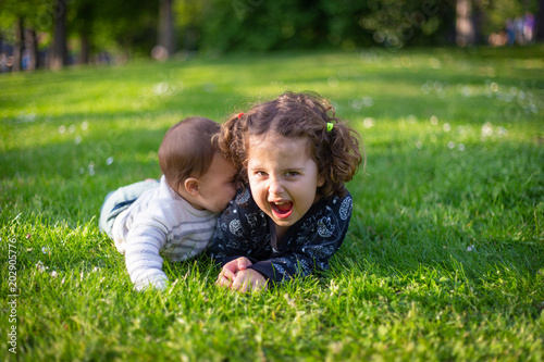 Two sisters playing in the grass in a park